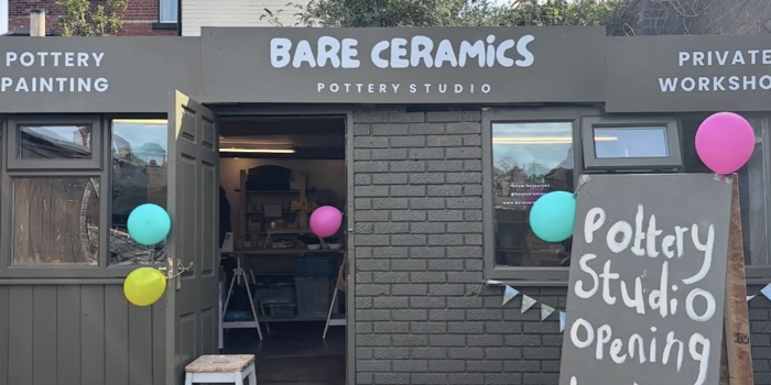 Exterior of Bare Ceramics pottery studio with open doors, colourful balloons, and a sign reading “Pottery Studio Opening Today,” showing the entrance and workshop space inside.