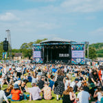 View from the back of the crowd sat out in front of the Tramlines main stage on a sunny summer's day 