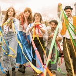 Five people walking down a road, throwing paper streamers.