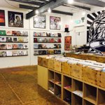 Inside Bear Tree Record, there are rows of wooden units holding records. On the walls new releases are displayed. One section of the wall has a floor to ceiling mural of the Bear Tree Records logo, painted by Sheffield artist Tom J Newell.