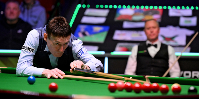 Jimmy White lines up a snooker cue on a table at the World Seniors-Snooker Championship with the crowd in the background 