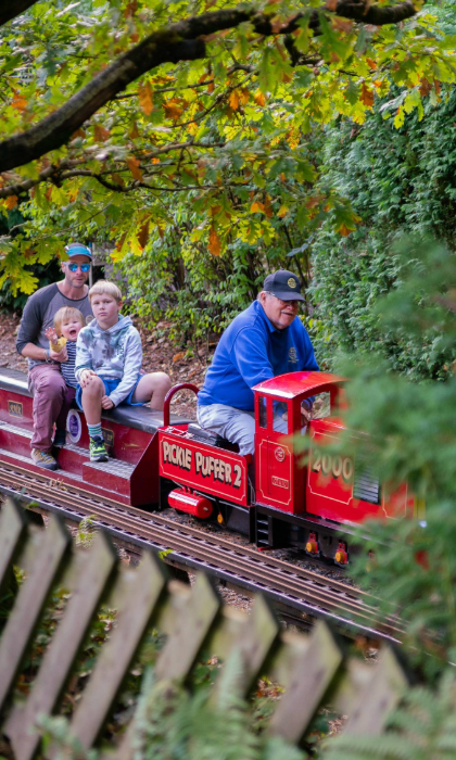A family rides on a miniature steam train through a wooded area at the Abbeydale Miniature Railway in Sheffield.