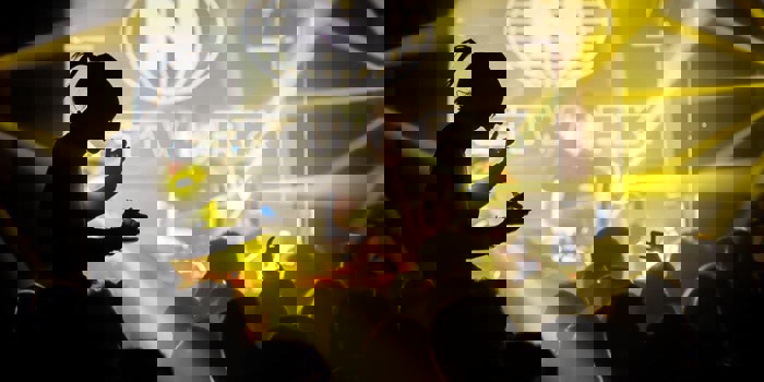 A nightclub full of people dancing, lit by yellow lighting.