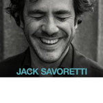 Black-and-white promotional image featuring a close-up portrait of a person with curly hair, eyes closed, and a broad smile. The person wears a dark jacket and is framed against a softly blurred background. At the bottom of the image, the name “JACK SAVORETTI” appears in large light blue capital letters.