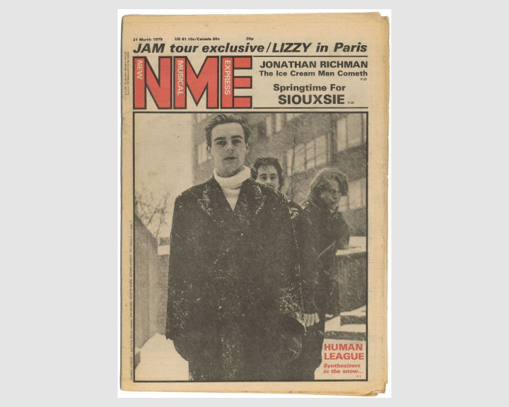A vintage magazine cover of NME (New Musical Express) dated 31 March 1979. The design features a sepia-toned photograph of three people standing outdoors in a snowy setting, wearing dark winter coats. The top section includes bold red “NME” branding and headlines such as “JAM tour exclusive / LIZZY in Paris,” “Jonathan Richman – The Ice Cream Man Cometh,” and “Springtime For Siouxsie.” A smaller text box at the bottom right reads “Human League – Synthesizers in the snow.”