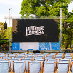 Rows of deckchairs in front of a large outdoor cinema screen.