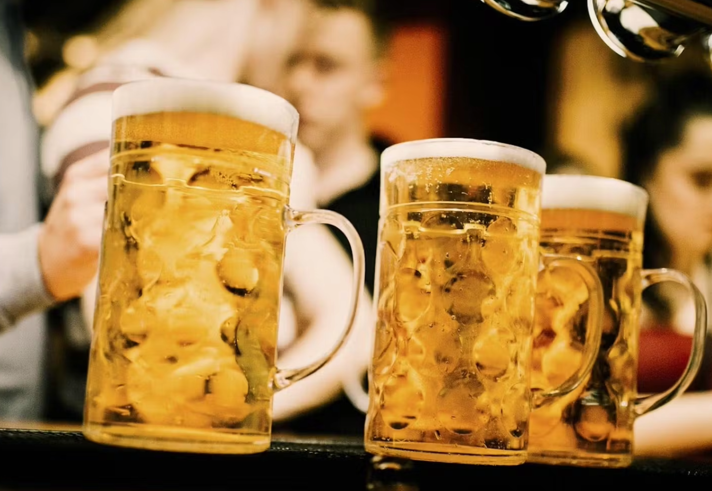 Three steins of beer on a bar top.