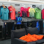 The interior of a shop, with lots of sporting clothes, shoes and equipment on display.