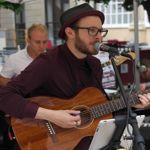A man singing into a microphone and playing and acoustic guitar in a restaurant.