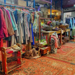 Inside The Warehouse with shelves and tables covered in things to buy and rails full of clothes.