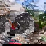 A woman climbing on a large rock. There is a thick safety mat on the ground below her.