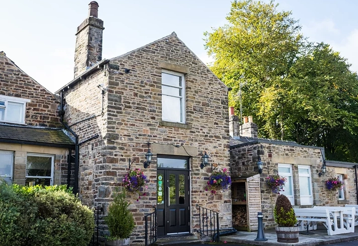 Exterior of The Cross Scythes pub showing the building and entrance.