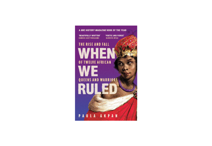 Book cover for When We Ruled: The Rise and Fall of Twelve African Queens and Warriors by Paula Akpan. Against a purple gradient background, large cream text displays the title. An illustrated historical figure in a red robe, gold crown and red jewel-studded headdress occupies the right side of the cover. Review quotes at the top describe the book as “Beautifully Written” and “Poetic and Fierce”. A banner states “A BBC History Magazine Book of the Year”. Author name at bottom.