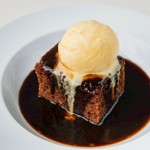 A cake covered in sauce with a scoop of ice cream on top.