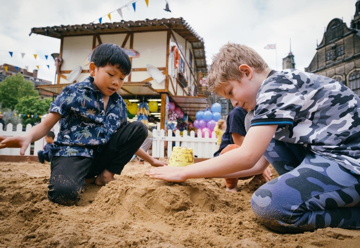 Children are playing in a sandpit that has been set up in the Peace Gardens in Sheffield city centre as part of the Sheffield By The Seaside event.