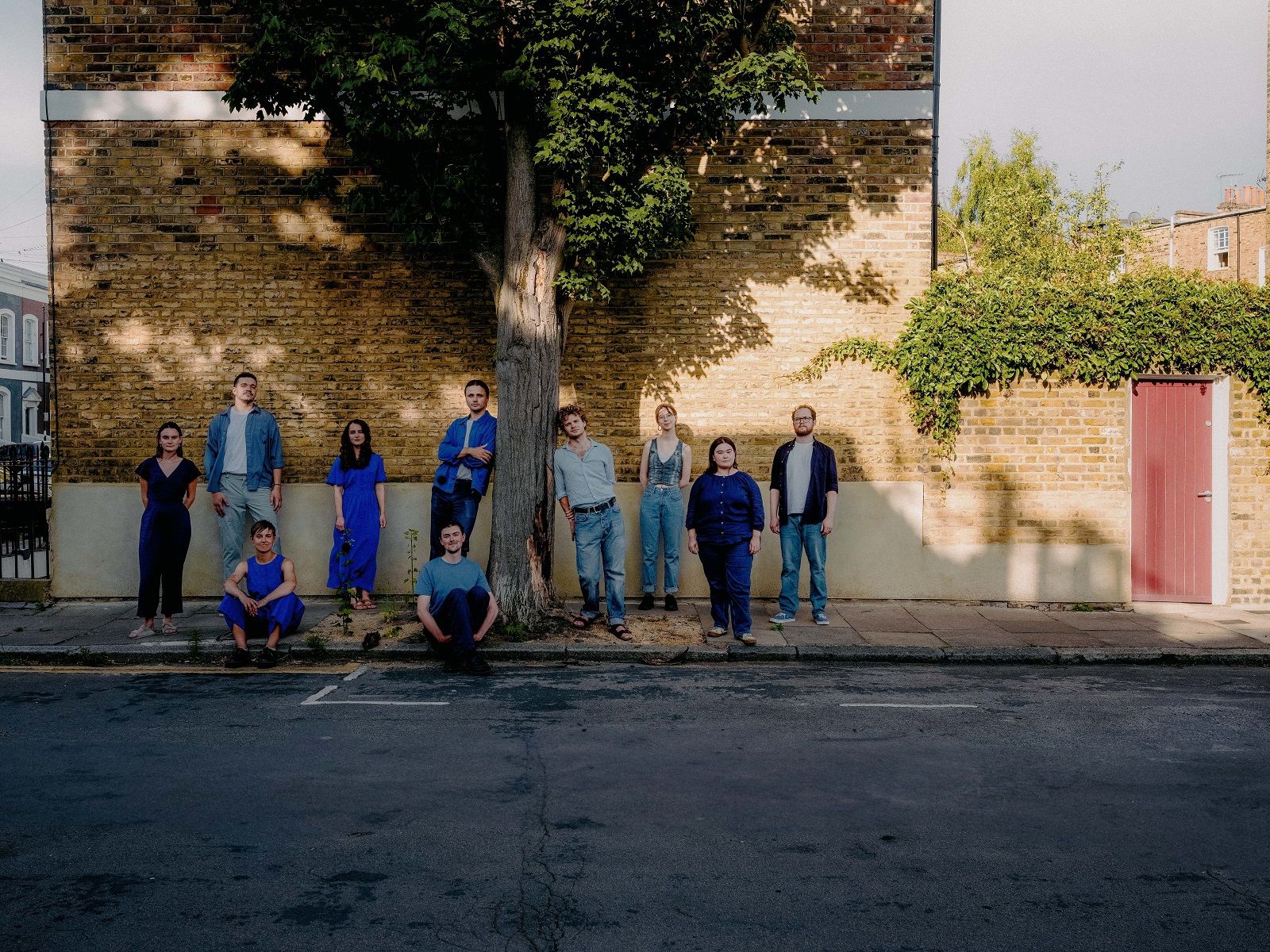 A group of people gathered around a tree on an urban street. Image credit: Ben Reason.
