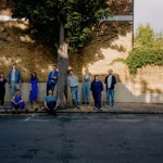 A group of people gathered around a tree on an urban street. Image credit: Ben Reason.