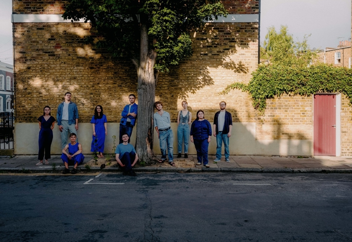 A group of people gathered around a tree on an urban street. Image credit: Ben Reason.