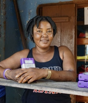 Two women stand leaning on a wooden shelf, looking directly at the camera and smiling.