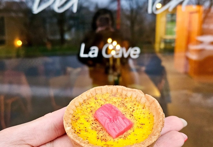 A hand holding an individual tart.