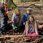 A group of children playing in a wooded area.