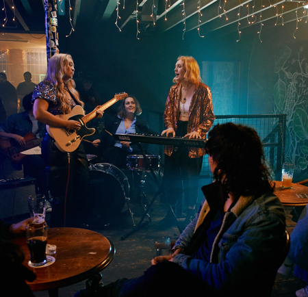 A three piece band plays live in front of a crowd at Alder.