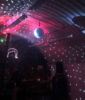 Dark club interior with pink and purple lights shining across a crowd on the dance floor, creating a vibrant nightlife atmosphere.