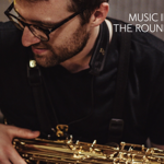 Close up of a man holding a saxophone in his lap.