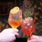 Two cocktails being held. 