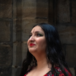 A person with long black hair, wearing a red dress with a floral design on the front.