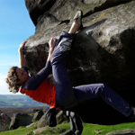 Two people climbing a boulder.