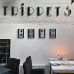A white washed brick wall with the Trippets Lounge Bar logo on it.
