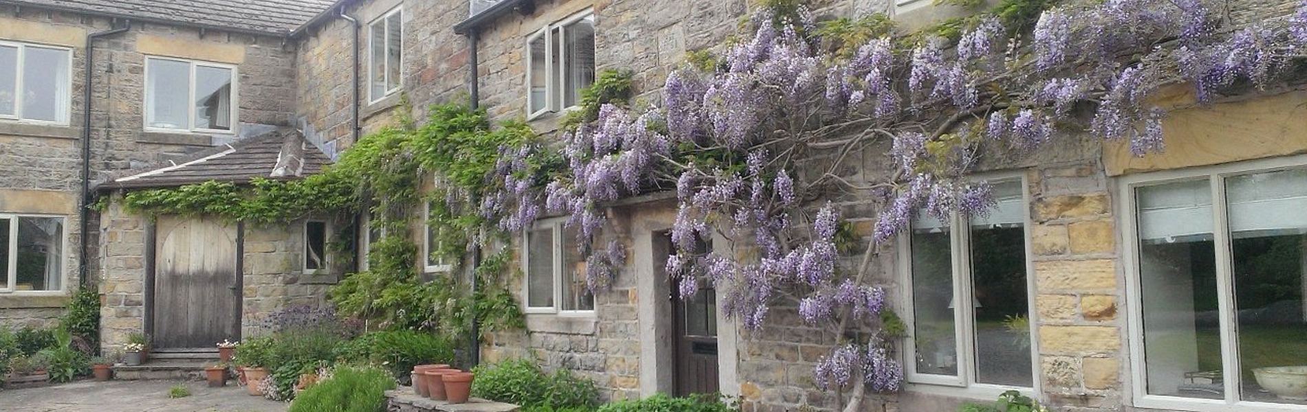 Loadbrook Cottage – exterior view with purple flowers hanging across the front of the building