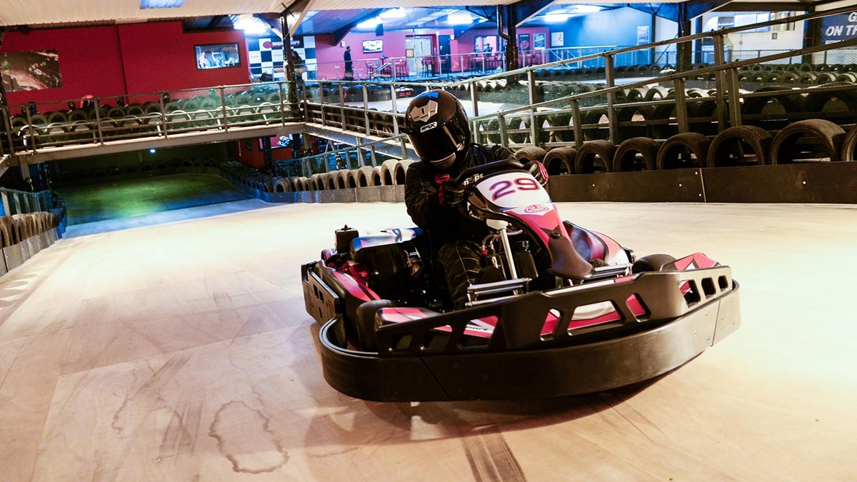 A person driving a go-cart on an indoor track.