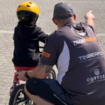 A coach teaching a child how to ride a bike.