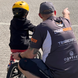A coach teaching a child how to ride a bike.