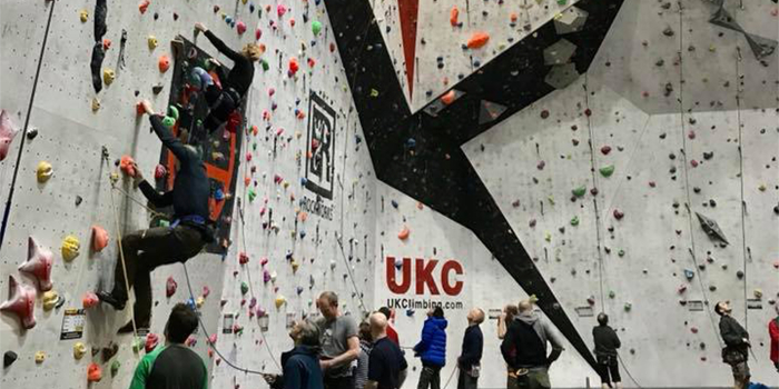 A big climbing wall at Awesome Walls Climbing Centre Sheffield. There are lots people climbing or waiting to climb.