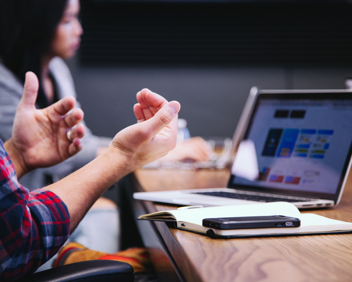 Two people, in casual dress, sat at a desk that has a laptop and paperwork on it. (Image © Hedway)