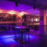 The dance floor and bar at Maida Vale, lit by purple lighting.