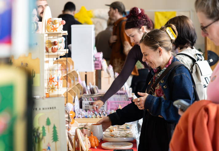 Crowds of people looking through stalls at an indoor market.