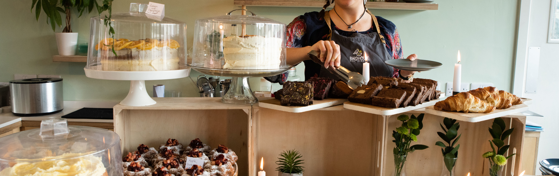 A woman works behind a counter cover in cakes of all different shapes and sizes.