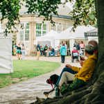 People sat under a tree at Art in the Gardens 2025 