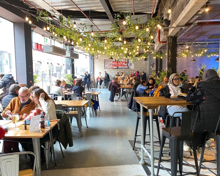 Inside Sheffield Plate, a bright an airy foodhall in Sheffield . There are lots of people sat at tables eating and chatting.