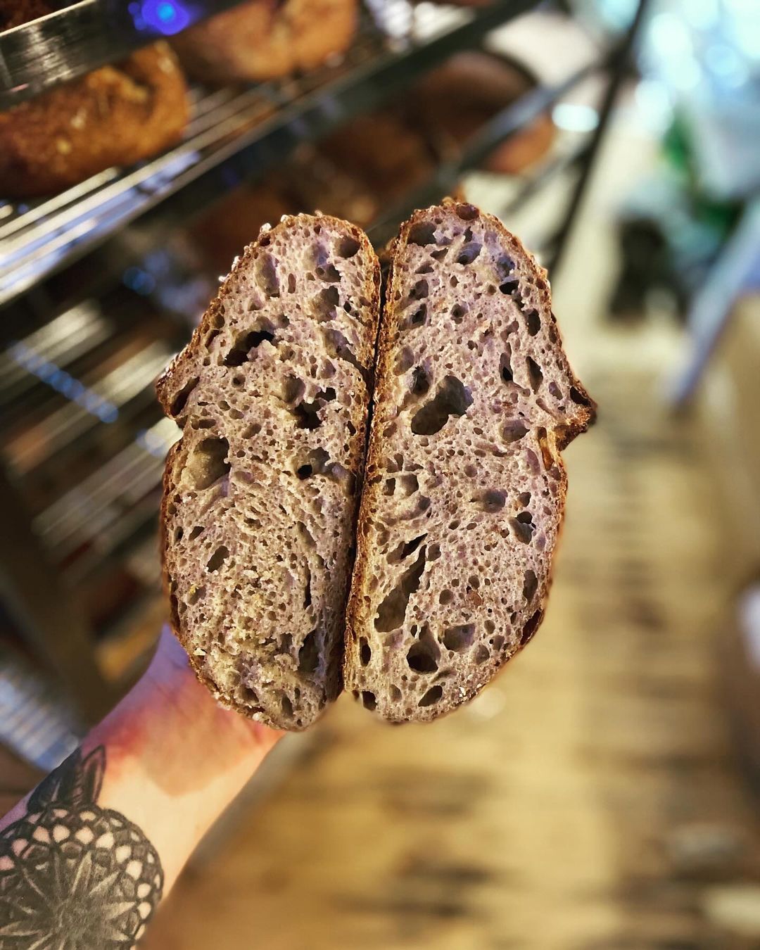 A hand holds a load of bread that has been cut in half.