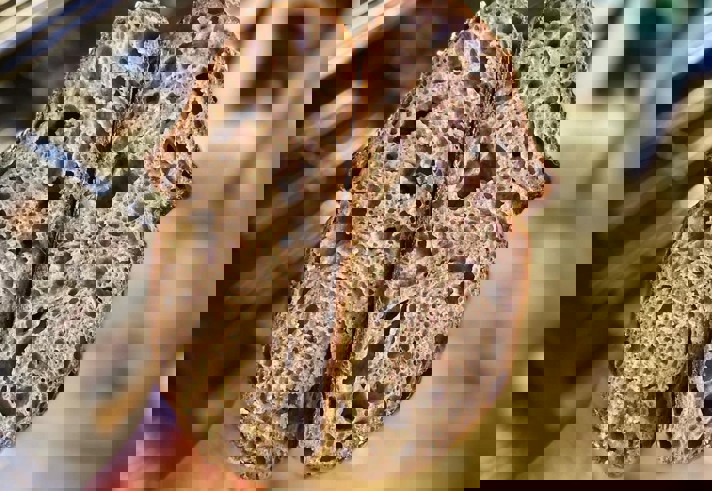 A hand holds a load of bread that has been cut in half.