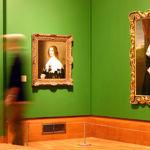 Inside Graves Gallery awoman walks past a painting.