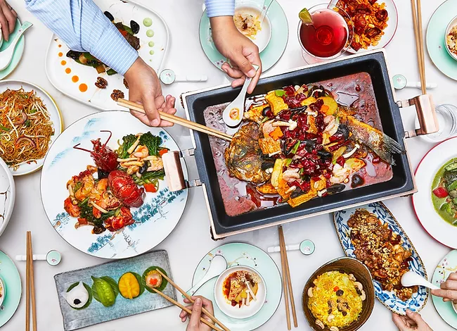 A large table, covered in a white cloth, and filled with plates and dishes of food.