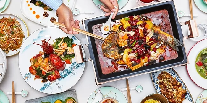 A large table, covered in a white cloth, and filled with plates and dishes of food.