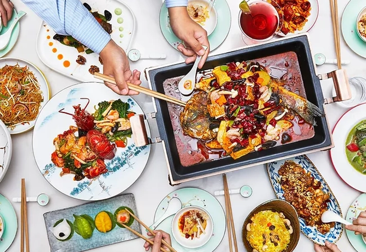 A large table, covered in a white cloth, and filled with plates and dishes of food.