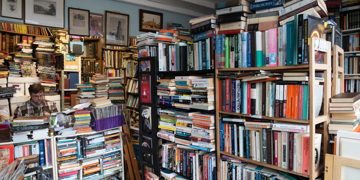 Interior of Porter Book Shop showing tall, densely packed bookshelves filled with a wide variety of second‑hand books. The room is full of stacked books, framed artwork on the walls, and an eclectic, cosy atmosphere typical of a classic used bookshop.